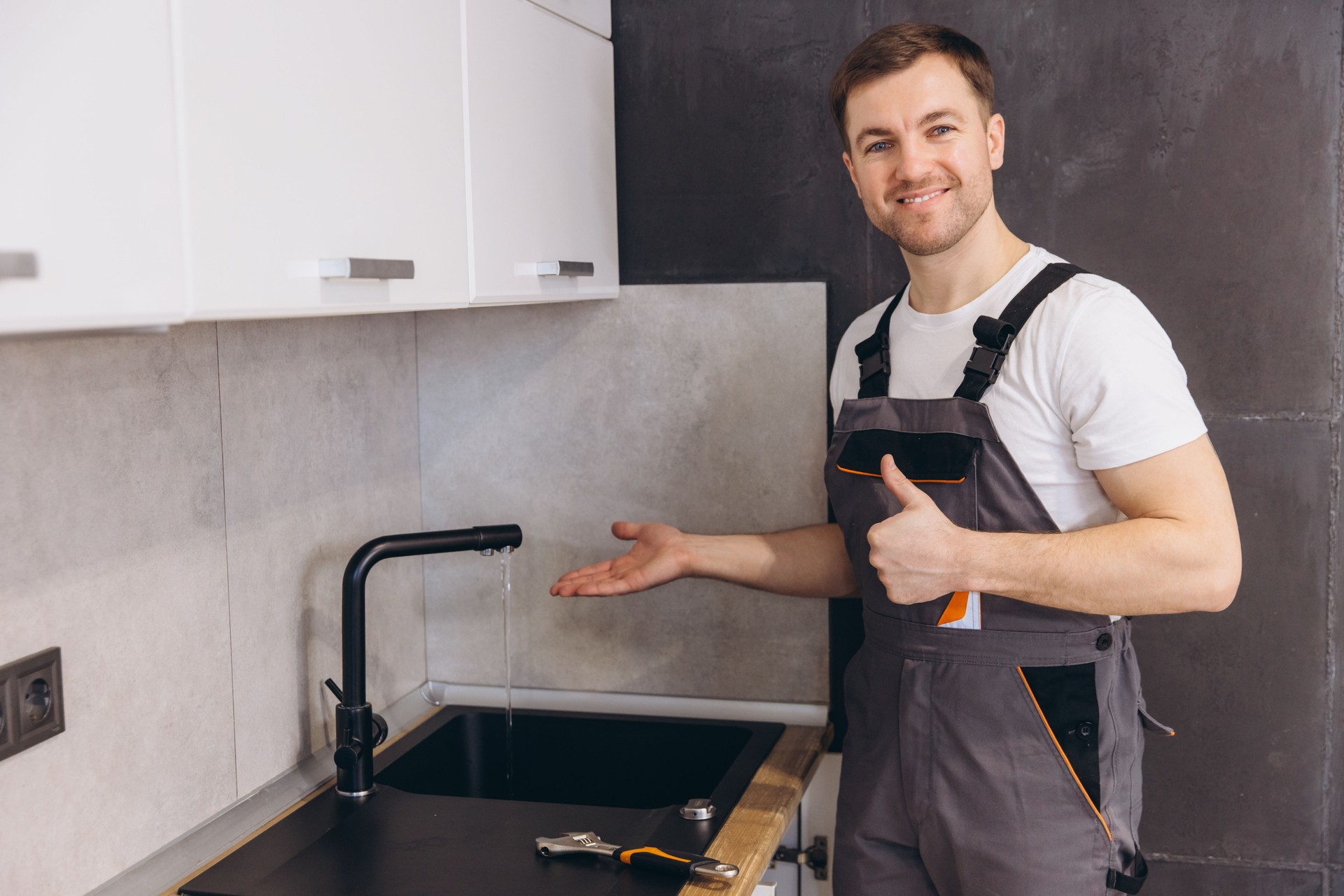 Plumber showing running water from tap after successful installation in kitchen